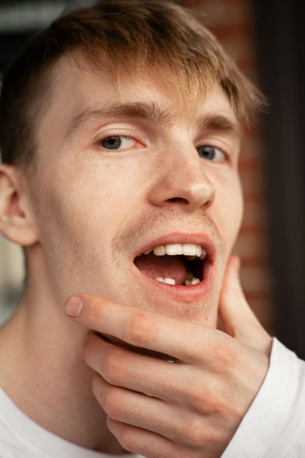 Close-up portrait of man with his jaw open and he is missing bottom teeth