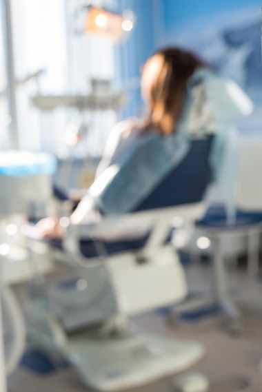 blurred dentist chair in a clinic with a woman sitting in it