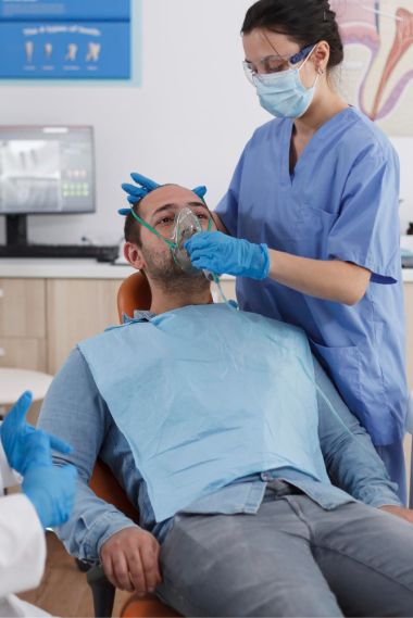 man in a dentist chair having oxygen mask  put on his face